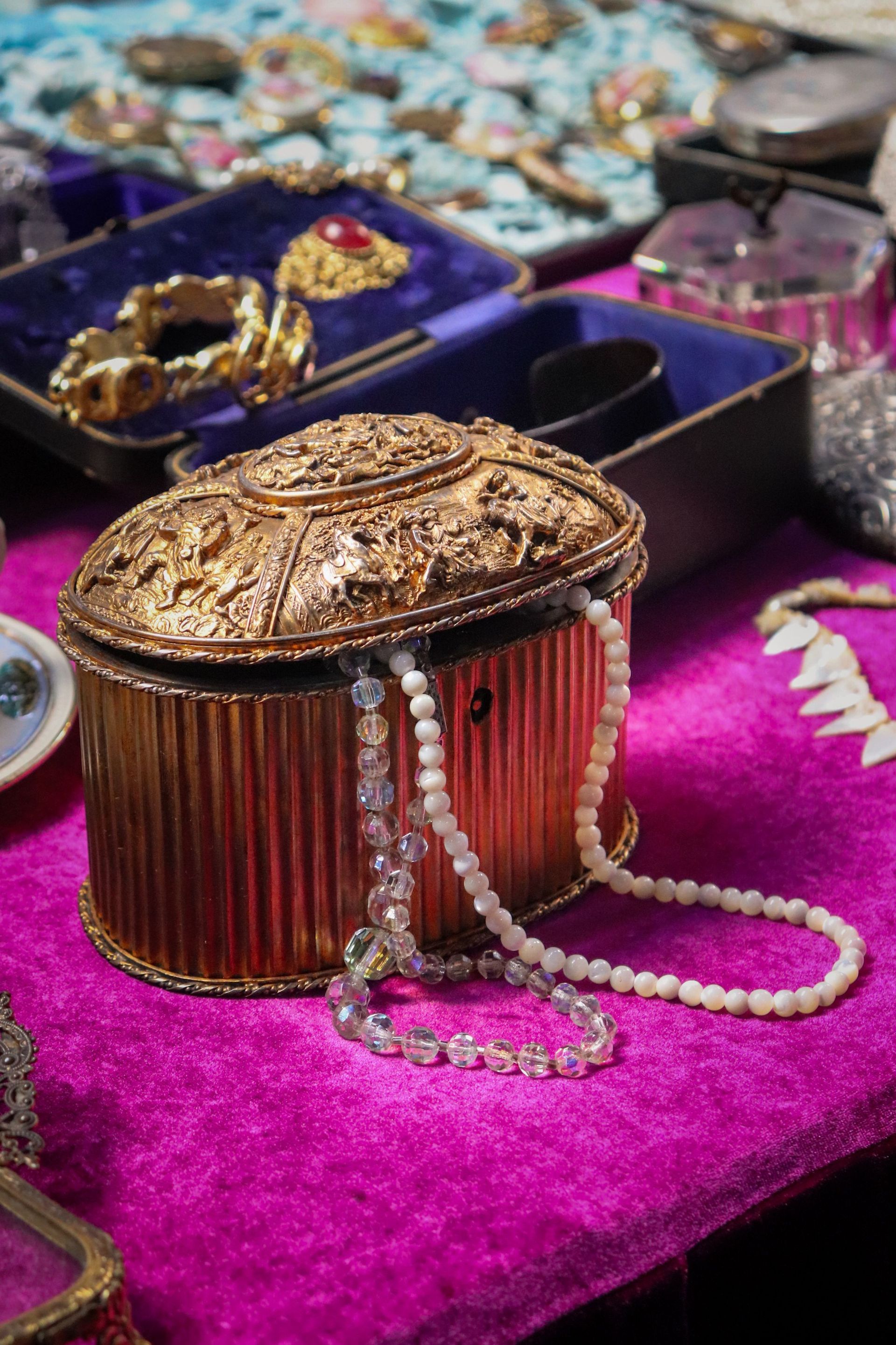 Ornate gold antique jewelry box adorned with pearls on a velvet surface, showcasing luxury and elegance.